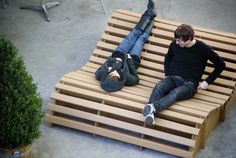 two young men sitting on wooden benches with their feet propped up against each other's legs