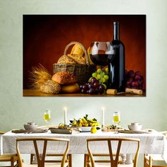 a table with wine, bread and grapes in front of a painting on the wall