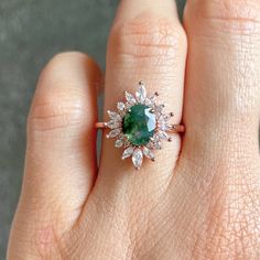 a woman's hand with a green and white diamond ring on top of it