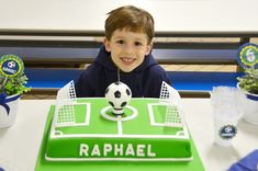 a young boy sitting at a table with a soccer themed cake