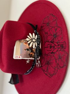 Be the life of the rodeo in this gorgeous boho red hat featuring a bull, poppies, and playful longhorns. Add this accessory to your wardrobe for a unique western touch. Western Cowgirl Hats, Adjustable Red Hat Bands For Spring, Adjustable Red Hat Bands For Kentucky Derby, Unique Hat Bands For Rodeo And Kentucky Derby, Vintage Hats For Western-themed Events, Unique Adjustable Hat Bands For Rodeo, Adjustable Red Festival Hat, Red Brimmed Hat For Festival, Red Country Style Hat