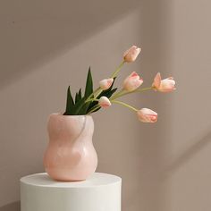 a pink vase filled with flowers on top of a white table