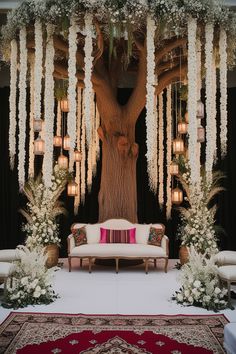 a white couch sitting under a tree filled with flowers