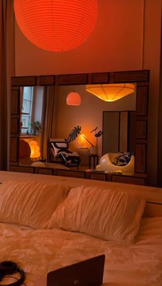 a laptop computer sitting on top of a bed under a red ceiling light in a bedroom