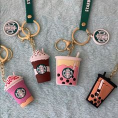 four starbucks keychains are shown on a blue blanket, one has a drink and the other is a cup