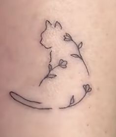 a small cat sitting on the back of a woman's leg with flowers in it