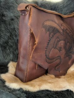 The Slumbering Dragon Messenger Bag We will make you a custom, unique bag just for you. Handmade, hand stitched, one of a kind leather messenger bag. It is made from extremely durable stone oil leather that offers beautiful color variation and texture as well as water resistance and lifelong use. The bag measures roughly 15 in by 13 in with a 3 in gusset. The front has three additional pockets one is 11.5 in by 8.5 in and the other two are 5 in by 6 in. The strap is completely adjustable and the Artisan Leather Satchel With Leather Lining, Handmade Leather Artisan Satchel, Handmade Brown Leather Briefcase, Handmade Leather Briefcase In Brown, Artisan Hand Tooled Leather Saddle Bag, Artisan Hand-tooled Leather Saddle Bag, Hand-stitched Leather Tote Satchel, Artisan Leather Satchel In Rectangular Shape, Artisan Rectangular Leather Satchel