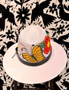 These vibrant hats are hand-painted in Oaxaca, Mexico, with vibrant flowers and a monarch butterfly around the hat's crown. Hat is made of canvas— light and breathable, but durable and waterproof. Elastic band inside the hat crown ensures a snug, secure fit. Hand Painted Brimmed Sun Hat For Spring, Hand Painted Curved Brim Sun Hat For Spring, Hand Painted Sun Hat With Curved Brim For Spring, Adjustable Hats For Cinco De Mayo Vacation, Adjustable Flat Brim Hat For Cinco De Mayo, Spring Festival Sun Hat Hand Painted, Spring Festival Hand Painted Sun Hat, Adjustable Western Hat For Cinco De Mayo, Hand Painted Fedora For Summer Festivals