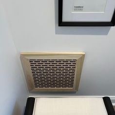 an air vent mounted to the side of a wall next to a white chair cushion