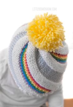 a baby wearing a knitted hat with a yellow pom - pom on top