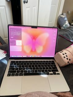 an open laptop computer sitting on top of a bed next to a pair of leg warmers