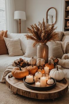 a coffee table with candles and pumpkins on it