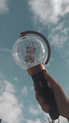 a hand holding a crystal ball with a skeleton on it and the sky in the background