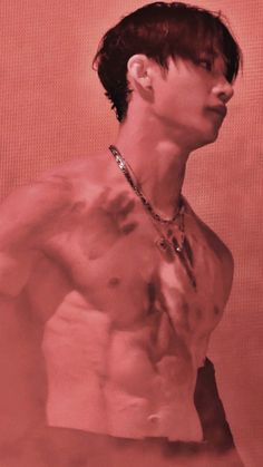 a man with no shirt standing in front of a red background