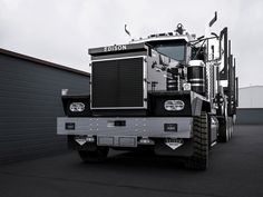 a black and white photo of a tractor trailer parked in front of a garage door