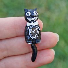 a small black cat figurine sitting on top of a hand