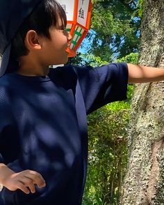 a young boy wearing a blue shirt and holding an orange frisbee in his hand