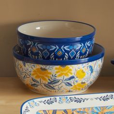 three blue and yellow bowls sitting next to each other on top of a wooden table