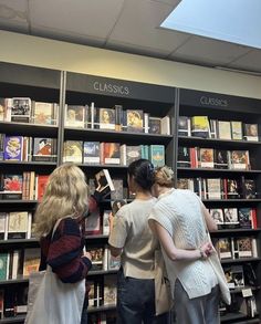 three girls are looking at books in a book store