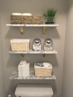 a white toilet sitting in a bathroom next to two shelves filled with baskets and towels