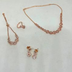 Elevate your style with this exquisite American Diamond CZ jewelry set in stunning rose gold. This set includes a necklace, bracelet, ring, and earrings, offering a complete and coordinated look for any special occasion. The intricate design and sparkling stones will make you the center of attention at weddings, parties, or formal gatherings. Product Details: Necklace: The centerpiece of this set, the necklace, features a dazzling American Diamond CZ pendant on a delicate rose gold chain. The adjustable chain allows you to find the perfect fit. Bracelet: The matching bracelet complements the necklace beautifully, with its American Diamond CZ stones set in a rose gold chain. It's designed to comfortably encircle your wrist and secure with a convenient clasp. Ring: The ring in this set showc Elegant Adjustable Jewelry Sets For Valentine's Day, Hand Set Round Jewelry Sets For Parties, Rose Gold Hand-set Round Jewelry Sets, Hand Set Rose Gold Jewelry Sets, Rose Gold Metal Jewelry Sets For Party, Adjustable Round Jewelry Sets For Celebrations, Rose Gold Cubic Zirconia Jewelry For Party, Elegant Rose Gold Jewelry Sets For Valentine's Day, Adjustable Pink Jewelry Set For Party