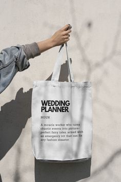 a person holding a white bag with the words wedding planner printed on it, against a wall