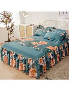 a bed with blue sheets and orange flowers on the cover is in a room next to a potted plant