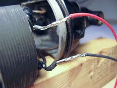 an electric motor with wires connected to it on top of a piece of plywood