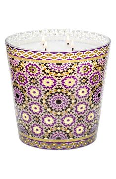 a candle that is sitting in front of a white background with purple and yellow designs