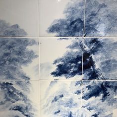 four blue and white tiles with trees on them in the middle one has been painted to look like clouds