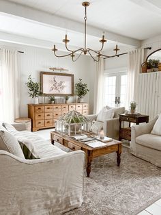 a living room filled with furniture and a chandelier hanging over the top of it