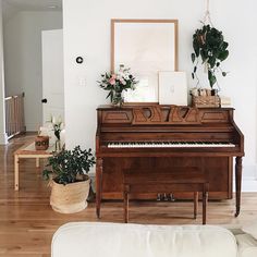 a living room with a piano and potted plants on the table in front of it