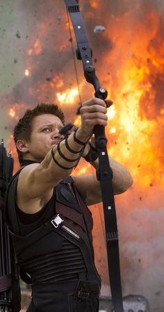 a man holding a bow and arrow in front of a sky full of exploding rocks