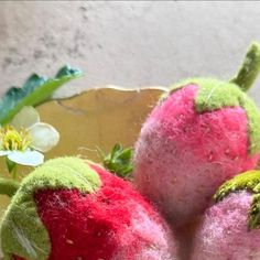 two red and green stuffed strawberries sitting on a table next to a flower pot