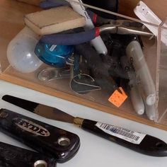 several different types of scissors and other items in a clear container on a table top