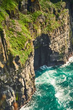 an aerial view of the ocean and cliffs in the far distance with green grass growing on them