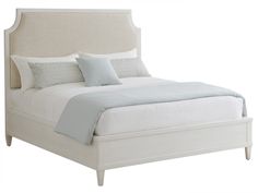 a bed with white linens and blue pillows on top of it, against a white background