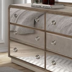 a silver dresser with mirrored drawers in a room