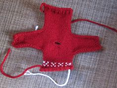 a red knitted object is laying on the floor next to an electrical cord and plugged in