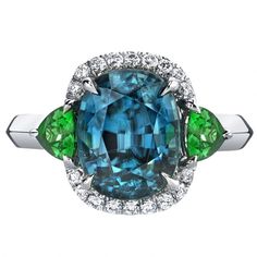 Omi Prive Cushion Blue Zircon, Trillion Tsavorite & Diamond Halo Ring in White Gold Green Diamond Rings, Golden Rings, Peacock Colors, Peacock Pendant, Diamond Halo Ring, Paint Brands, Golden Ring, Zircon Jewelry, Blue Cushions