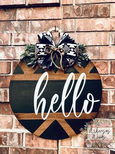 a wooden sign that says hello hanging on the side of a brick wall with a bow