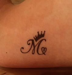 a woman's lower arm with a crown tattoo on her left side and the letter m in the middle