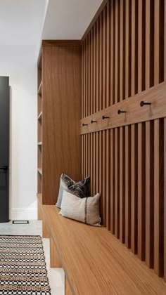 a wooden bench sitting in the middle of a hallway next to a black refrigerator freezer