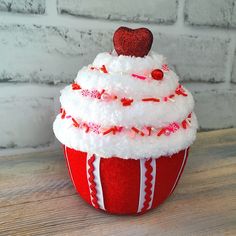 a red and white cupcake covered in frosting on top of a wooden table