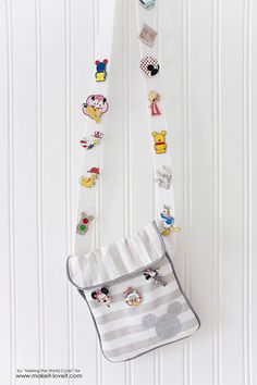 a purse hanging on the wall with pins and magnets attached to it's side