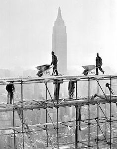 construction workers are on scaffolding in front of the empire state building