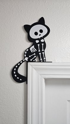 a black and white cat is sitting on top of a doorknob with a skeleton painted on it