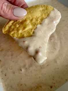 a person dipping some kind of food into a white sauce in a bowl with a spoon