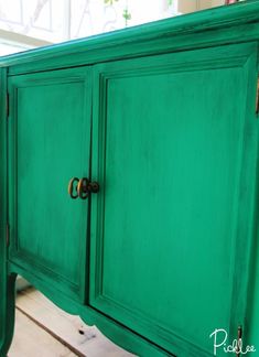 a green cabinet with brass handles and knobs on the doors is painted bright green