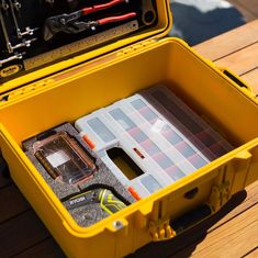 a yellow tool box filled with tools on top of a wooden table